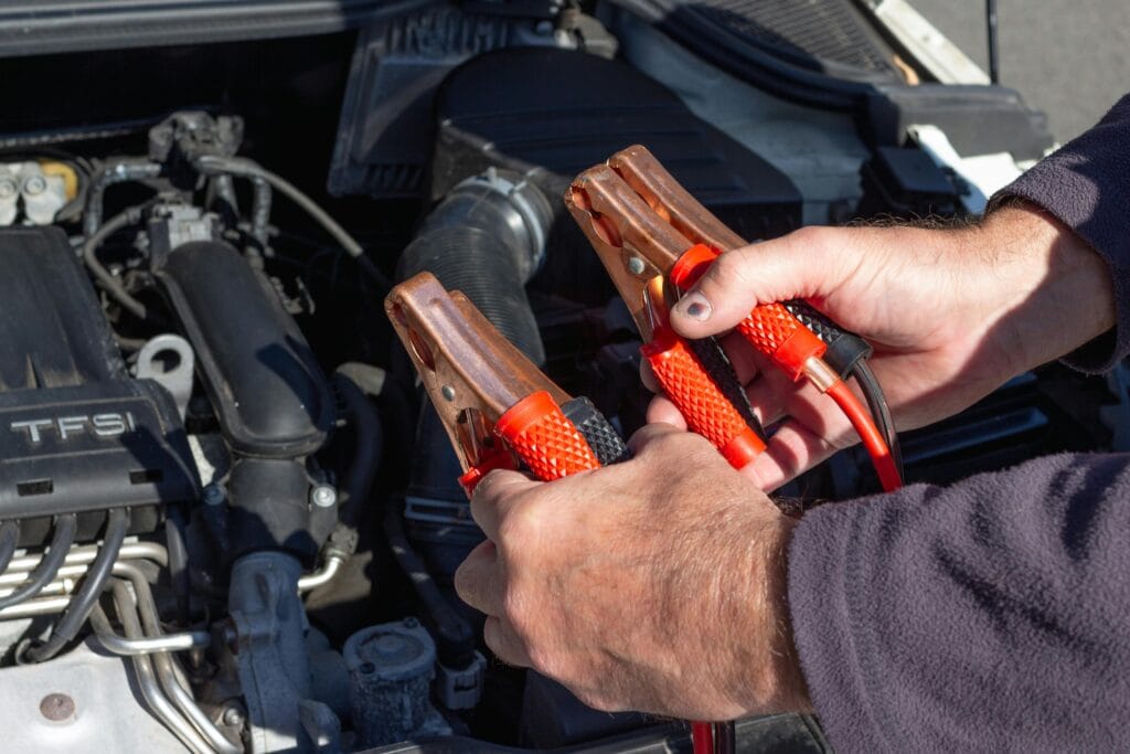 hands holding jumper cables for battery service